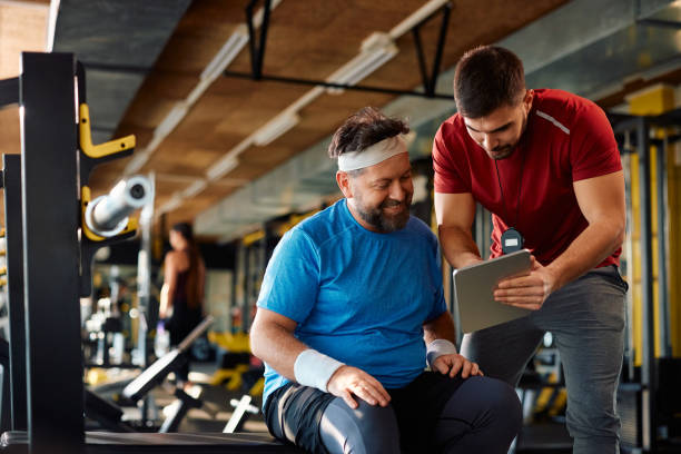 istock Happy mature athlete and his coach using touchpad during exercise class in a gym. 1988015155