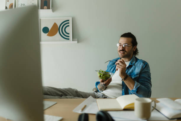 istock Young man working at home office and eating salad 1988015161