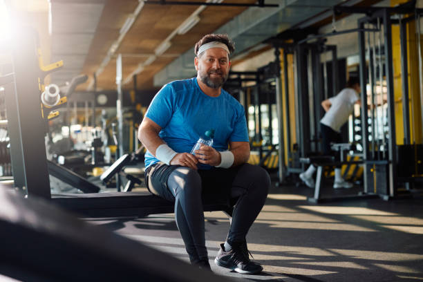istock Smiling mature athlete having water break during gym workout and looking at camera. 1988015166