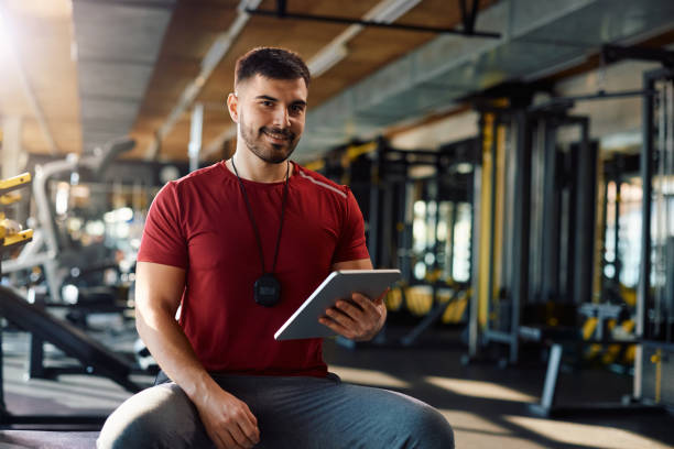 istock Happy coach using digital tablet in a gym and looking at camera. 1988016215