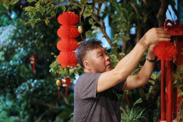 An Asian senior man is preparing Chinese New Year decoration at home