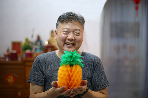 An Asian senior man is preparing Chinese New Year decoration at home