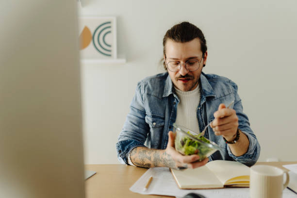 istock Young man working at home office and eating salad 1988017835
