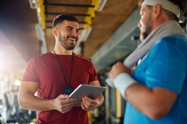 istock Happy personal trainer talking to his mature client in a gym. 1988021473