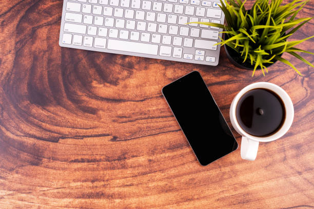 Wooden desk with coffee, smartphone  and computer keyboard flat lay