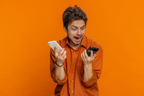 istock Irritated stressed business man talking on two mobile phones having conversation conflict quarrel 1988057141