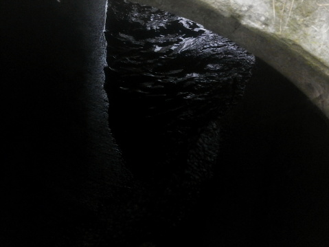 The eerie glint of water flowing through a dark pipe