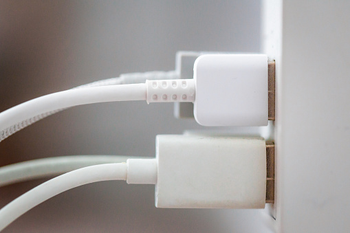 Macro close up image depicting white USB cables plugged into a power adaptor.