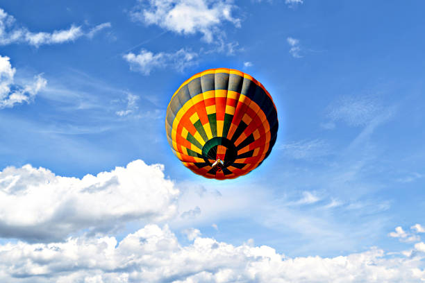Trees being skimmed by a hot air balloon descending into a wooded valley looking for somewhere safe to land