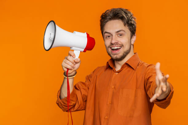 istock Caucasian man talking with megaphone proclaiming news loudly announcing advertisement discounts sale 1988077861