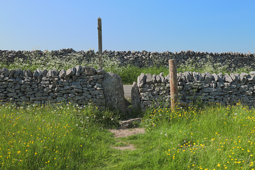 a drystone wall in the foreground of a footpath forming part of the Cleveland way on the North Yorkshire moors on a bright sunny day