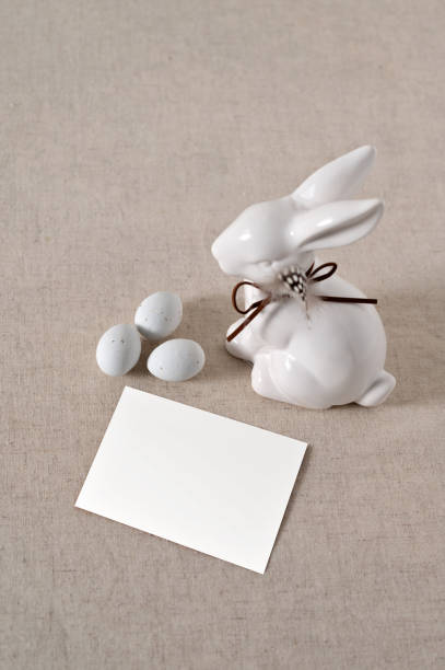istock Minimalist aesthetic Easter still life, blank paper card mockup, rabbit figurine, small eggs on neutral beige linen cloth background 1988140890