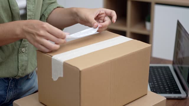 Hands of female consumer stick barcode on cardboard box with yellow sticker with word Return