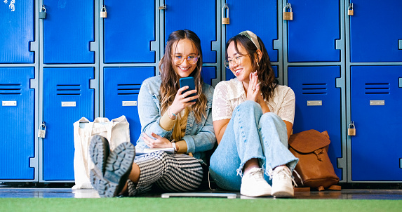 Happy woman, friends and phone by lockers for social media, communication or networking at college. Female person or students on mobile smartphone in relax for online texting or chatting in corridor