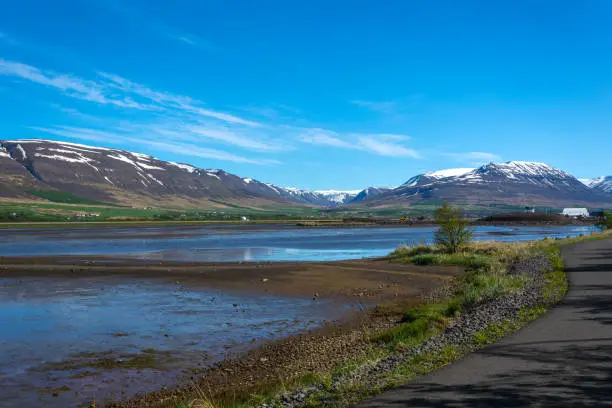 Photo of Icelandic landscape with a road in the foreground and snow-capped mountains in the background
