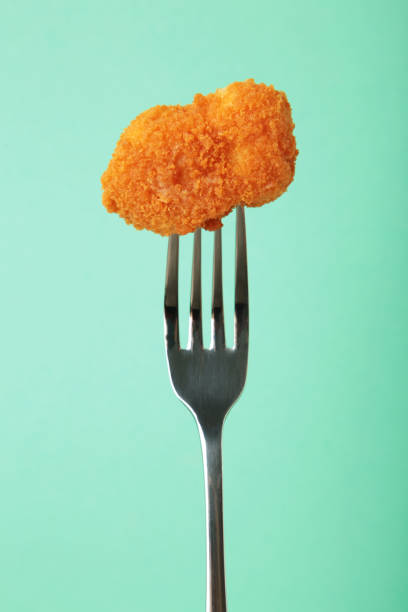 istock Chicken nugget on a fork on mint background. Vertical photo 1988220336
