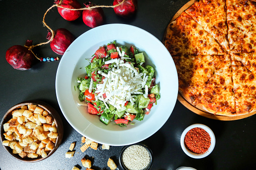 A table set with a delicious, freshly made salad and a mouth-watering pizza.