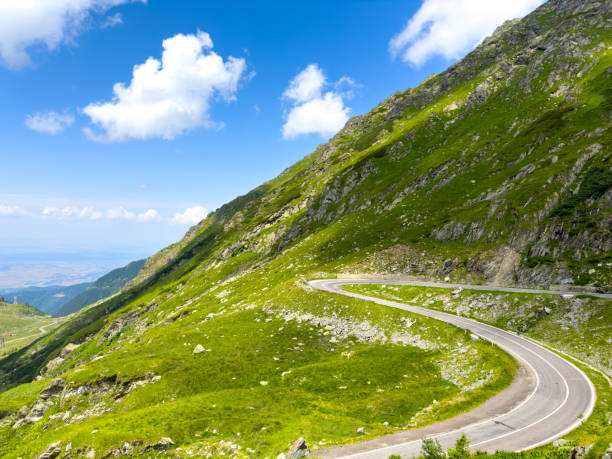 istock A delightful road in green mountains with a slightly cloudy blue sky 1988240334