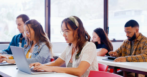 istock Woman, student and laptop in classroom for studying, education or learning at university or college. Young female person, learner or academic scholar on technology for online research, exam or test 1988242947