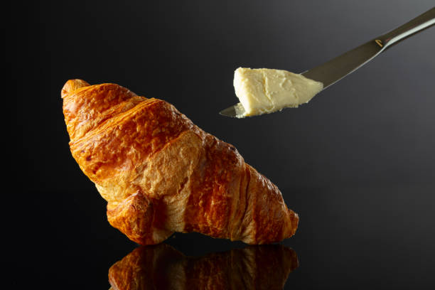istock Fresh baked croissant with butter on a black background. 1988247190