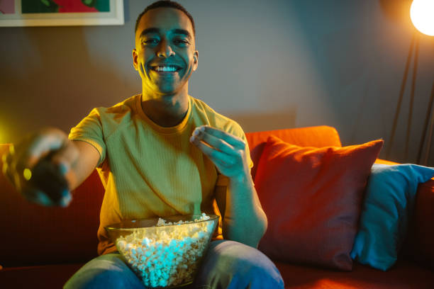istock Young man watching TV at night 1988263526