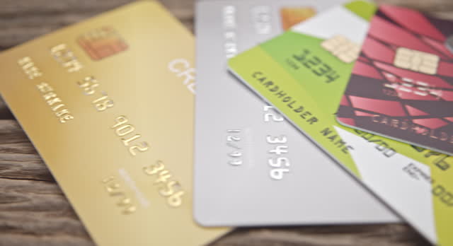 Credit card debt, electronic fund transfer, unsecured consumer debt and personal finance concept : A sweeping panoramic perspective capturing a collection of assorted credit cards gathered in a pile.