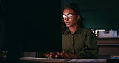 Business woman, reading on computer and night research for information technology and software solution. Young programmer or developer with glasses, planning and typing on desktop in a dark office