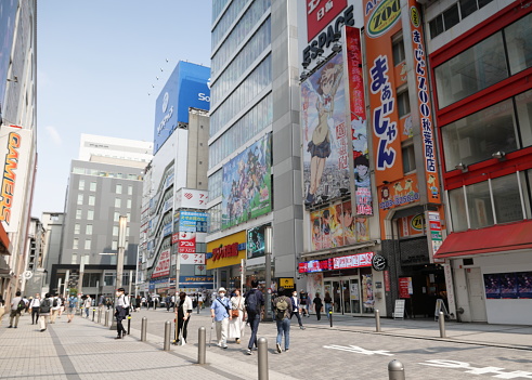 Chiyoda City, Japan - May 22, 2023: Pedestrians walk under the colorful commercial signs lining Sotokanda in Akihabara District. Spring afternoon in the Tokyo Metropolis.