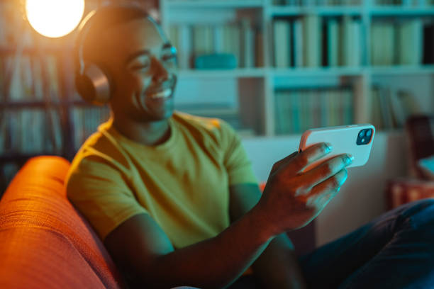 istock Young man watching online content on smart phone at home 1988285081