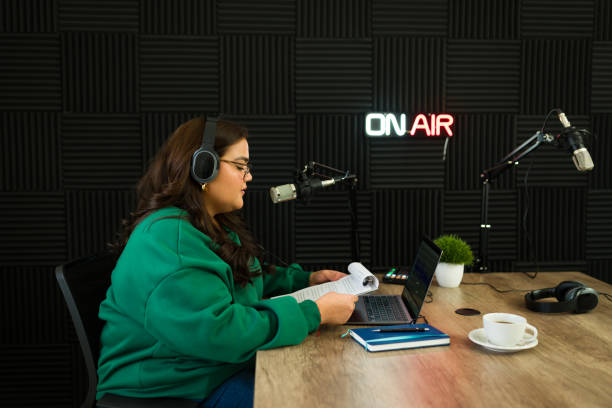 istock Hispanic woman reading a script recording a podcast in the studio 1988296185