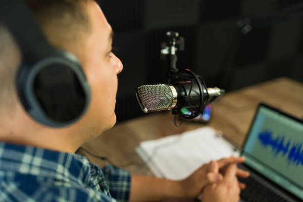 istock Hispanic podcast host with a laptop recording in the studio 1988303799