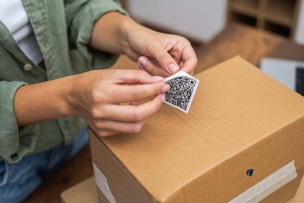 istock close up woman attaches qr code sticker to cardboard parcel to return and receive a refund. 1988303918