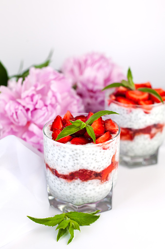 Natural dessert with fresh strawberry, yogurt, chia seeds and fresh mint on the table. Healthy breakfast. lose-up.