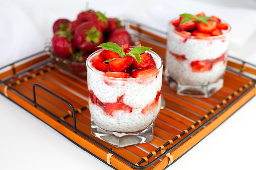 Healthy breakfast of strawberry, yogurt and chia seeds on on a wicker tray. Homemade natural dessert. lose-up.