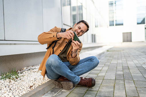 Modern man playing video games on smartphone outdoors