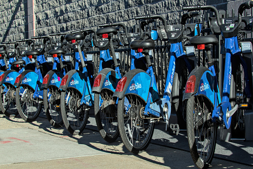 Brooklyn, NY - Feb 4, 2023: Long row of Citibike corporate sponsored bike share bicycles docked in a dock bay on a street in New York City.