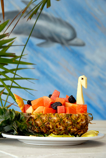 Plate of fresh fruit, fruit figure with pineapple and papaya in the shape of a swan