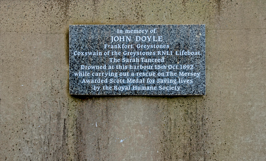 The plaque on the harbour wall in Greystones, County Wicklow, commemorating the Greyatones RNLI Coxswain, John Doyle, who drowned here in 1892.