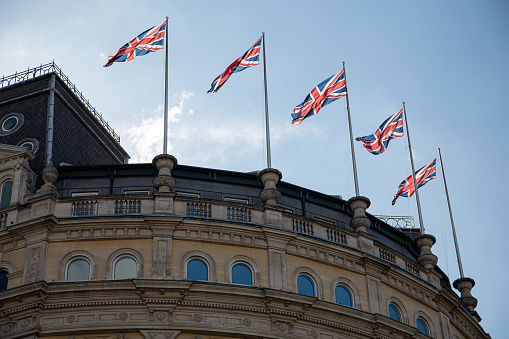 The Grand Hotel London, UK in Trafalgar Square with British flays flying in the wind and backlit by the late day sun.