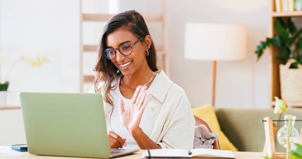 istock Woman, video call and computer for home education, e learning introduction and happy communication. Indian person or student waves hello on laptop for virtual planning, PhD meeting or online course 1988407033