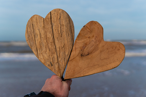 Hearts made of wood against the backdrop of a sandy beach and waves