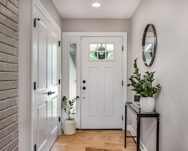 A cozy entryway with brown walls and a white front door. A cozy entryway with brown and brick walls, hardwood flooring, decorations, and a white front door with windows. building entrance stock pictures, royalty-free photos & images