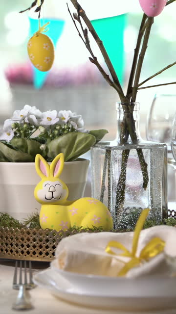 Young woman setting Easter festive table with bunny and eggs decoration