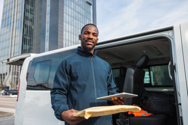 istock Cheerful Delivery Driver With Van and Package 1988456942