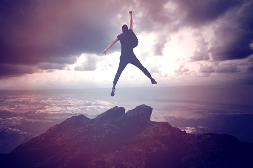 Businessman Jumping on Mountain