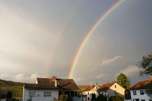 Rainbow over the house after a storm with clouds in the city. Panoramic view of beautiful sunset.