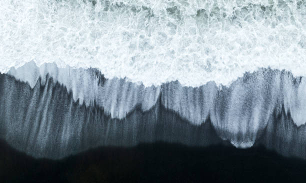 waves crashing on black sand beach - gaviotas volando sobre el agua y la playa fotografías e imágenes de stock