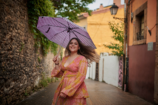 Happy woman, umbrella and walking in neighborhood for sightseeing, holiday or weekend vacation and travel in London. Female person or tourist smile and cover for stroll or rainy weather in urban town