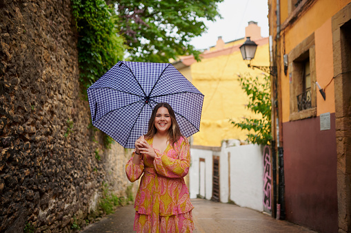 Portrait, travel and happy woman with umbrella in city street for walking, explore or adventure in Italy. Freedom, cover or plus size female person outdoor in Venice for holiday, journey or vacation