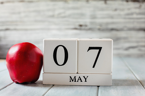 White wood calendar blocks with the date May 7th and a red apple for National Teacher Appreciation Day.